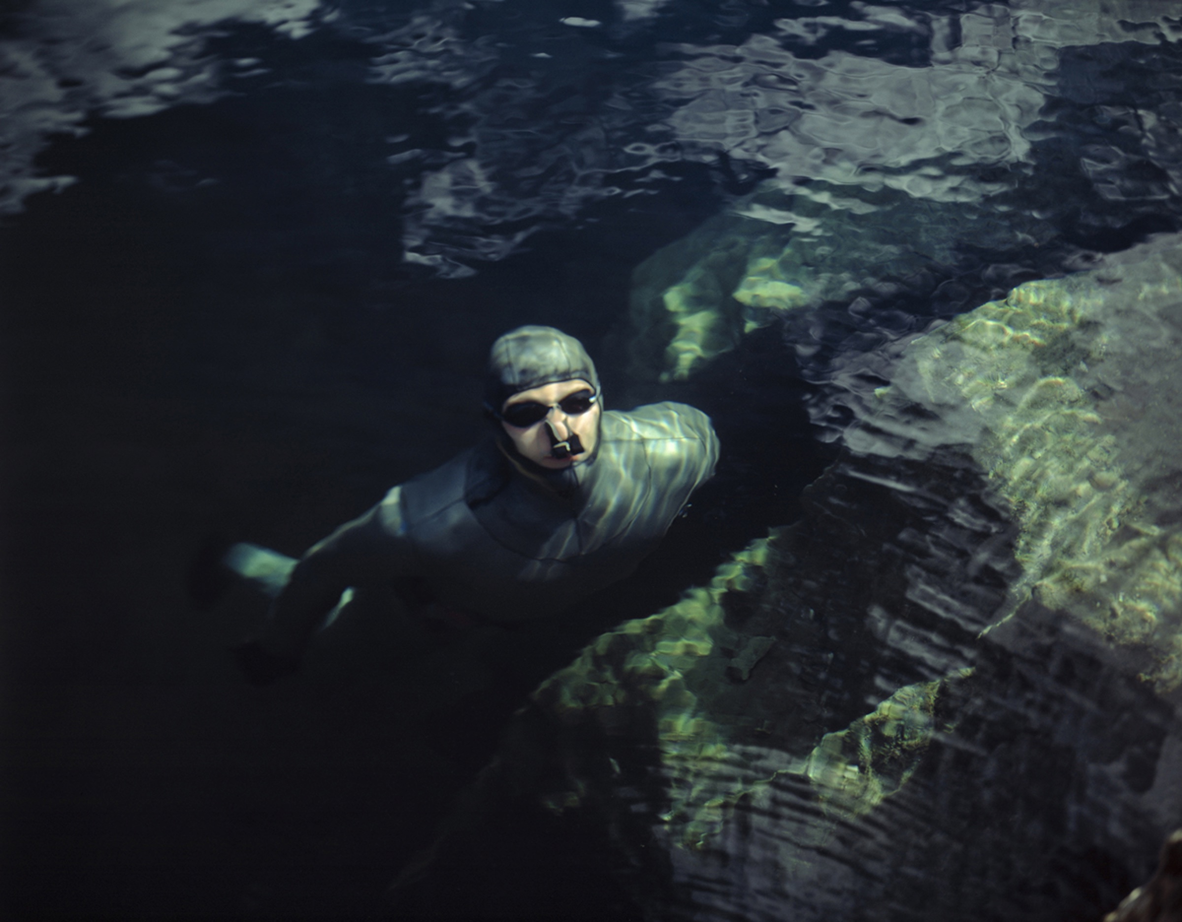 Freediver stretching — arms reaching, body suspended at dusk