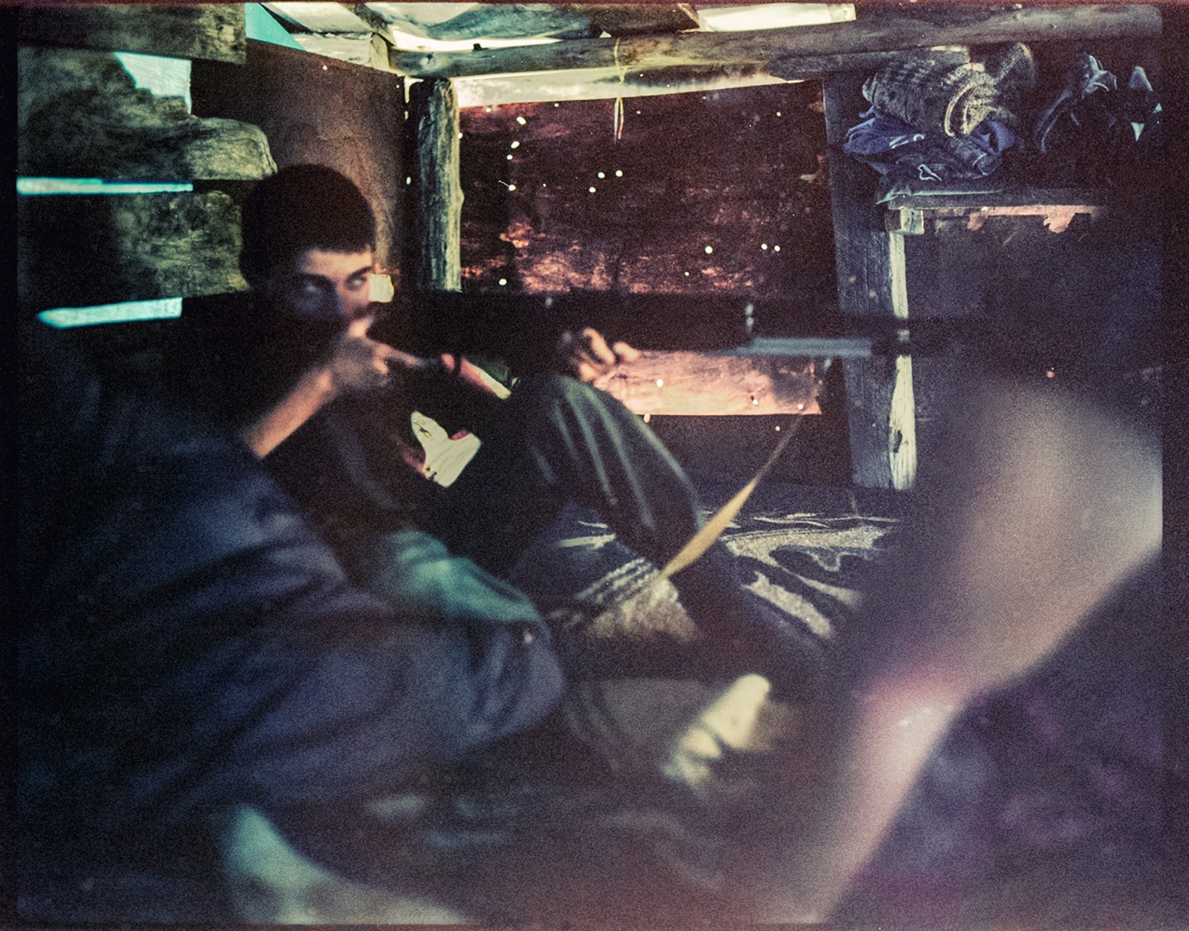 Man inside a dark wooden interior, a rifle resting nearby — Pankisi Valley