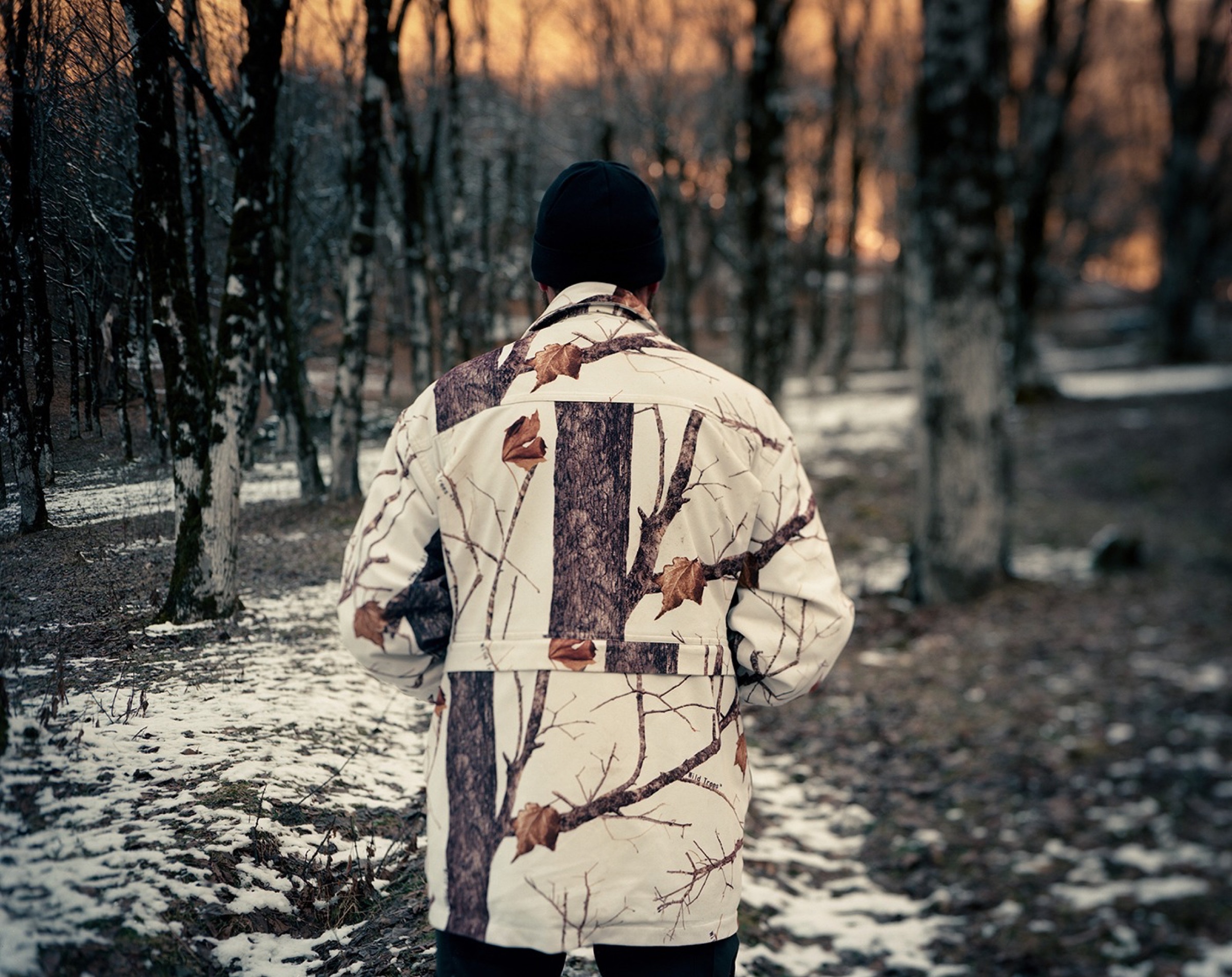 Man from behind in a winter forest, camouflage jacket, late evening light — Pankisi Valley