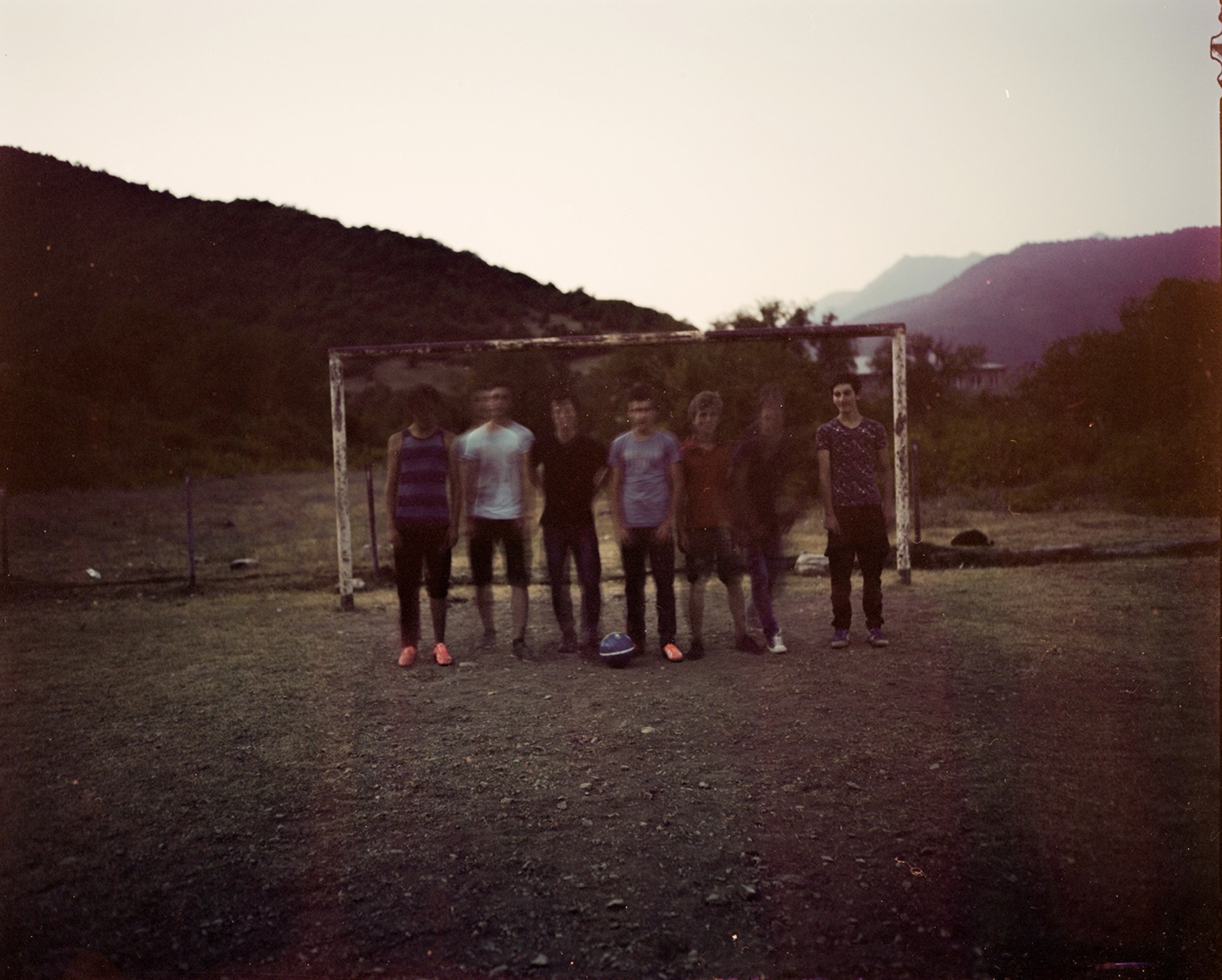 Group of boys standing at a makeshift football goal at dusk, mountains behind — Pankisi Valley