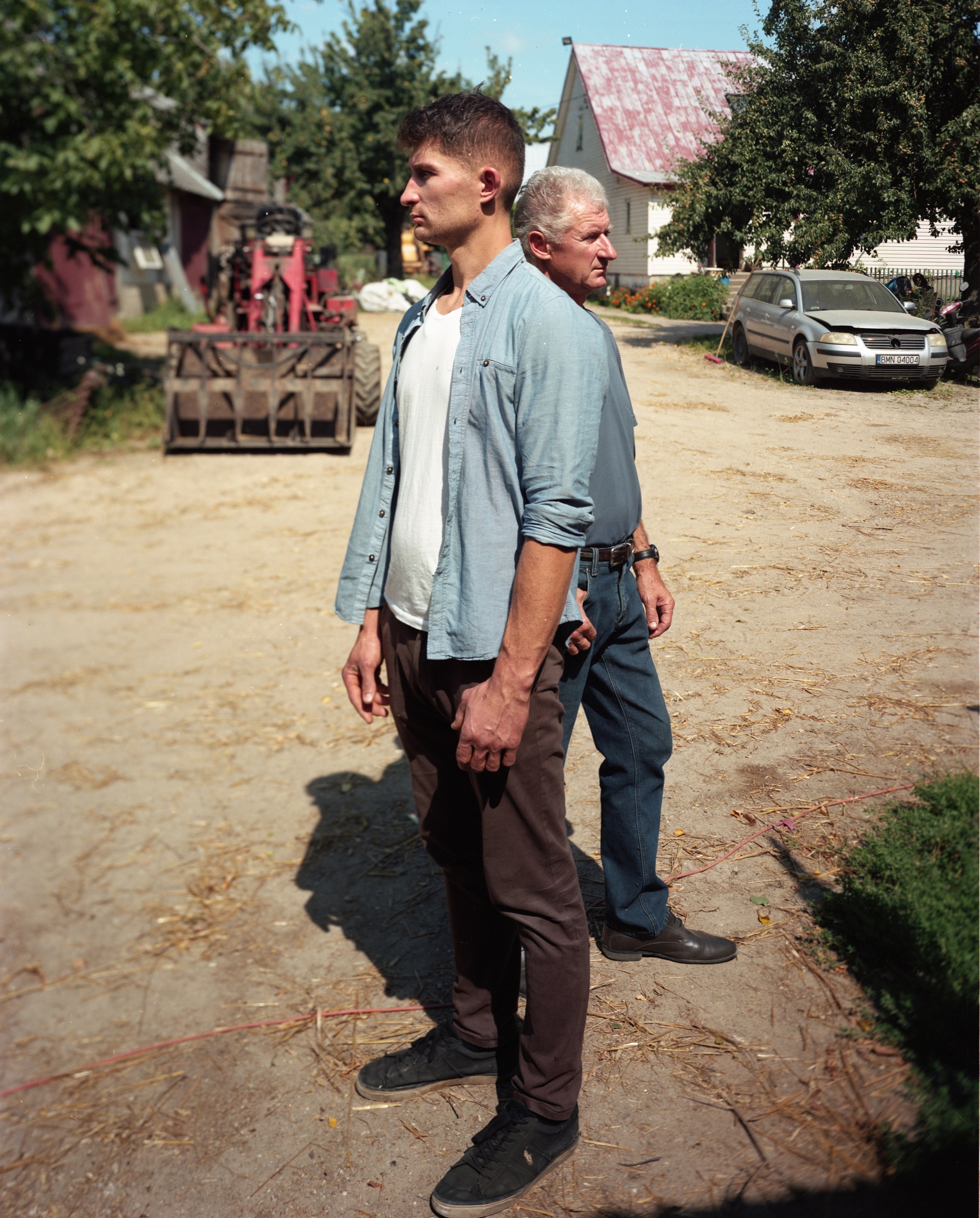 Young man and older man standing side by side in a farmyard — Podlasie