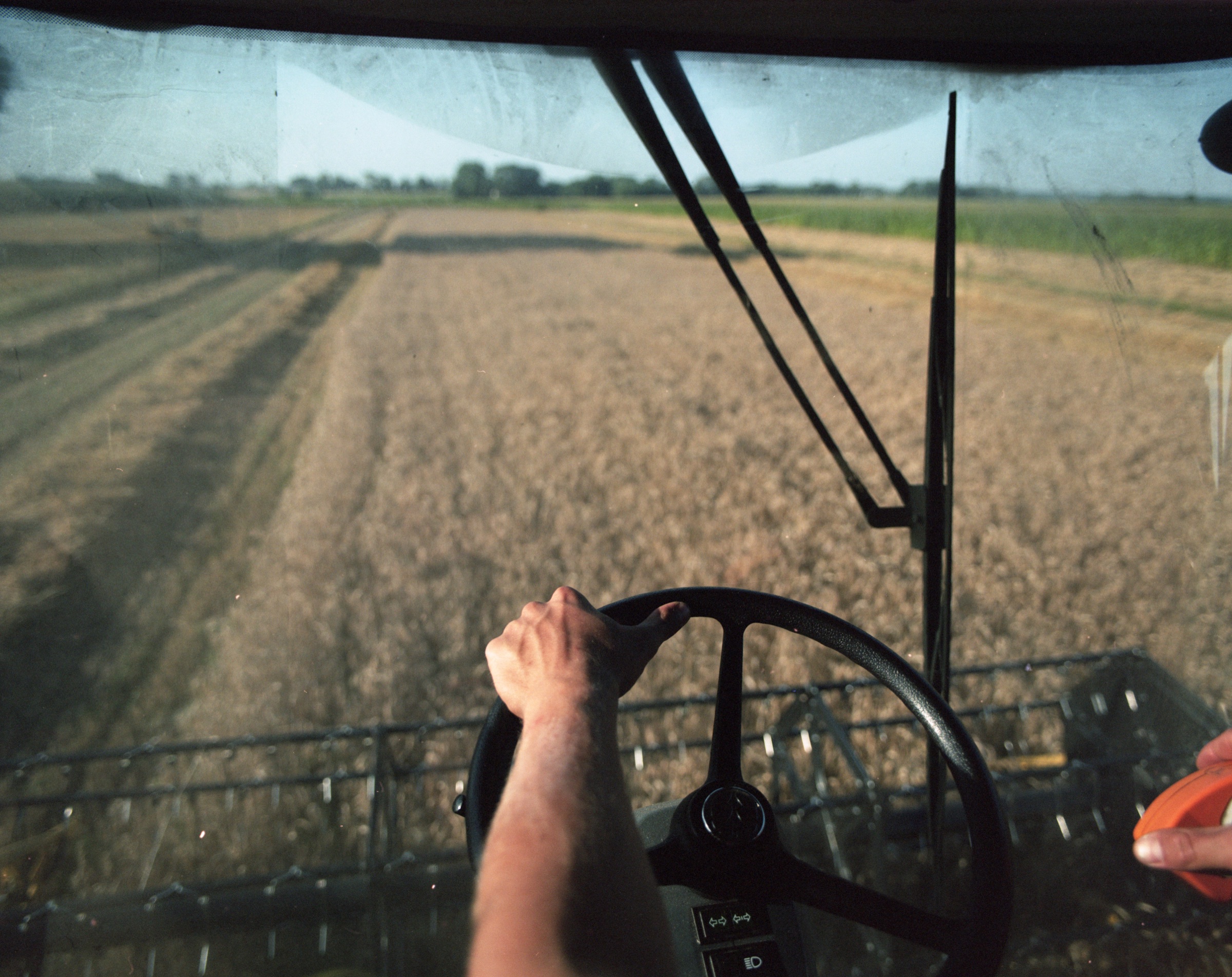 Inside a combine cab — hand on the steering wheel, grain field ahead — Podlasie
